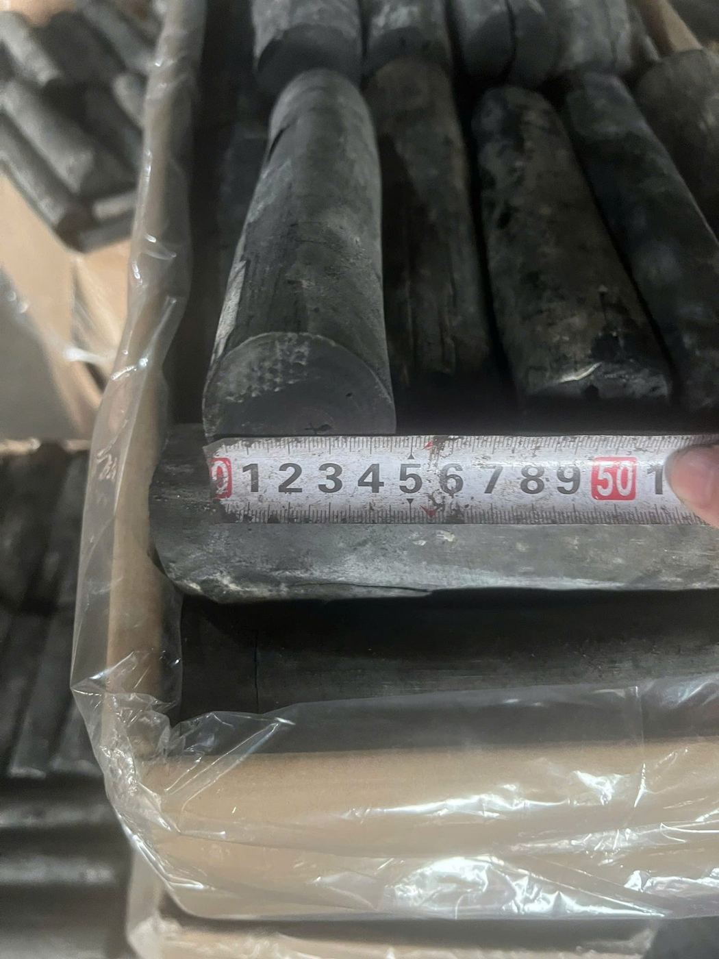 Charcoal stick measured against a size reference scale