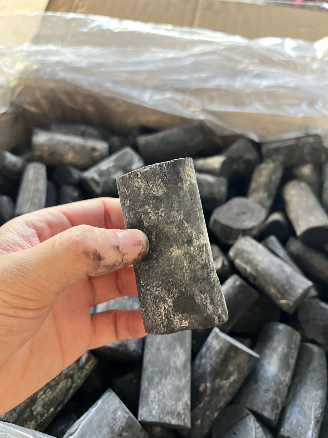 Hand holding a charcoal piece for quality inspection