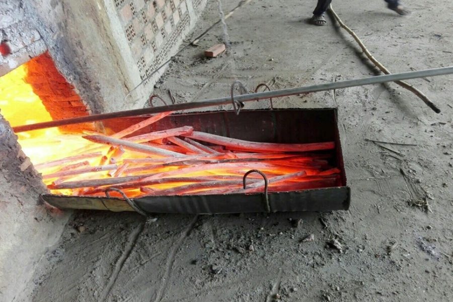 Hot charcoal raked out of the kiln into a metal trough